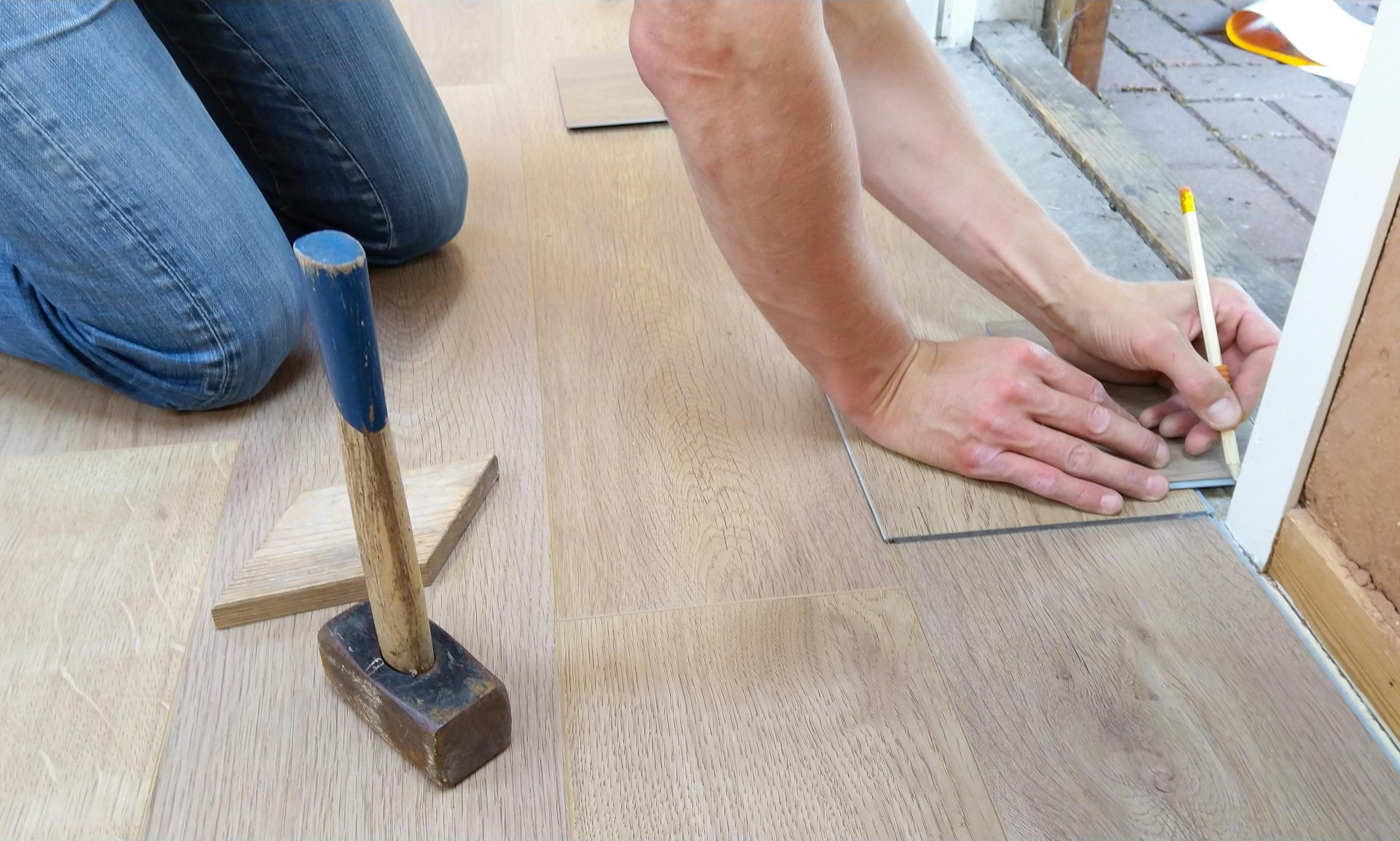 Un artesano mide y marca cuidadosamente los paneles de piso de madera para una instalación precisa.