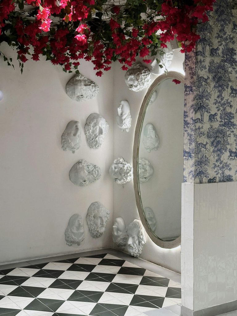 Interior elegante con techo floral y esculturas artísticas en la pared en Playa del Carmen.